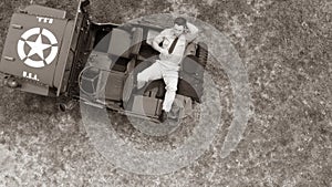 Overhead, drone, looking down on Male army officer in uniform resting on back of military vehicle