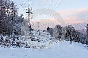 The overhead electric line over blue sky. Electrical wires of power line or electrical transmission line covered by snow in the