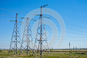 Overhead electricity transmission lines in the summer, against the background of the blue sky. .