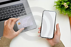 Overhead, Female hands holding her smartphone and credit card over her modern working desk