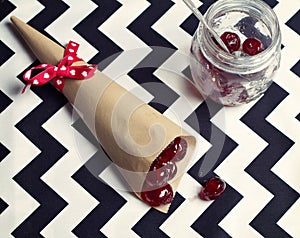 Overhead of glace cherries in a cone and vintage jar