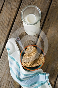 Granola bar and milk with napkin on wooden table