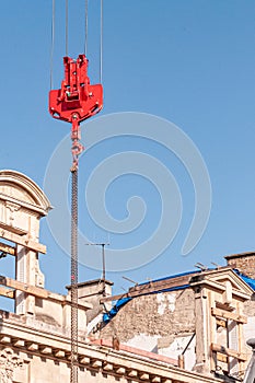 Overhead, Industial, crane hoist and hook, and 1500\'s building, against a blue sky