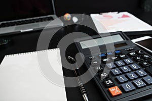 Overhead of office table with notebook, computer keyboard, calculator