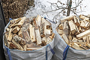An overhead perspective of transport bags filled with birch firewood on a winter-spring day.