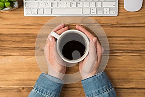 Overhead photo of computer keyboard mouse plant and cup of coffee  on the wooden backdrop