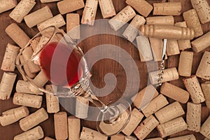 Glass of red wine with corks and corkscrew on a dark rustic background with a place for text, toned image