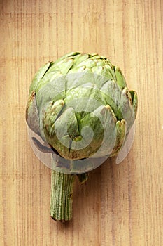 An overhead photo of a globe artichoke on a rustic wooden background