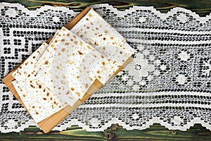 An overhead photo of matzah or matza piece on tthe chopping desk on lace doily. Matzah on the wooden table for the Jewish Passover photo