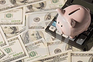 Overhead photo of piggybank pink pig with calculator isolated on the background of dollars