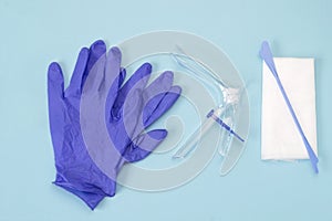 An overhead photo of the vaginal speculum, white napkin, medicine gloves and spatula. Medical plastic tool for holding open the va