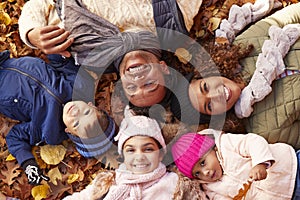 Overhead Portrait Of Family Lying In Autumn Leaves