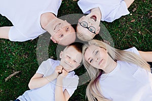 Overhead portrait on family lying on grass in park.