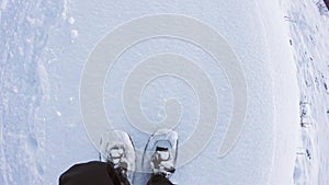 Overhead POV man hiking and walking with snowshoes outdoor on white snowy path in mountain wild field in winter. Detail