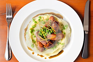 overhead shot of bangers and mash with peas on a plate