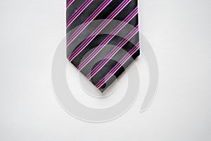 Overhead shot of a black tie with purple stripes on a white surface