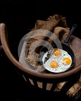 Overhead shot of cast-iron pan with three fried eggs sprinkled with black pepper