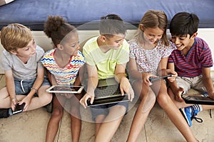 Overhead Shot Of Children Sitting On Floor Using Technology