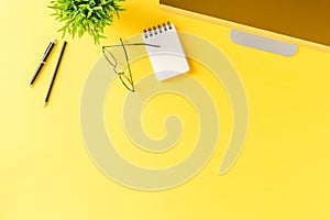 Overhead shot of computer and business accessories on yellow background. Office desktop.