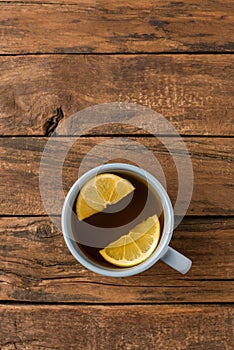 Overhead shot of cup of tea with silce of lemon on white wooden table