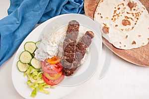 Overhead shot of delicious flatbread wrap koobideh with fresh vegetables and tzatziki sauce