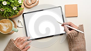 Overhead shot of female hands using mock up digital tablet with stylus pen on white desk