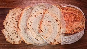 Overhead shot of a freshly baked, sliced sourdough bread on a wooden board