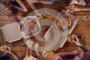 Overhead shot of friends at a table sharing take-away pizzas