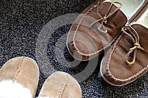Overhead shot of generic ladies and mens slippers on a dark gray