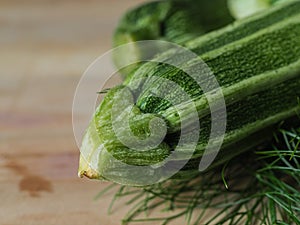 Overhead shot of a group of  isolated three green biologic zucchini veggies fruit over a light brown table and a paper recycled