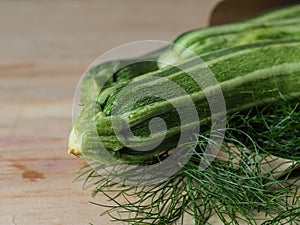 Overhead shot of a group of  isolated three green biologic zucchini veggies fruit over a light brown table and a paper recycled