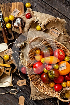 Overhead shot of homegrown assorted red, yellow, orange tomatoes in wicker straw basket