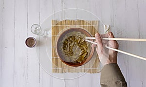 Overhead shot of a Japanese shoop with chopsticks on a white wooden background