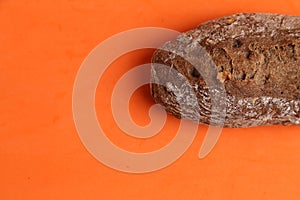 Overhead shot of a loaf of brown bread isolated on an orange background