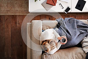 Overhead Shot Looking Down On Woman At Home Lying On Sofa Watching Television