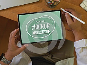 Male worker using mock up digital tablet on wooden table