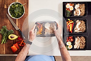 Overhead Shot Of Man Preparing Batch Of Healthy Meals At Home In Kitchen