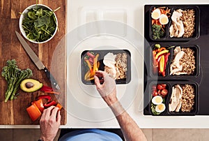 Overhead Shot Of Man Preparing Batch Of Healthy Meals At Home In Kitchen