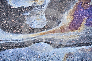 An overhead shot of the mesmerizing patterns created by leaking gasoline on wet ground.