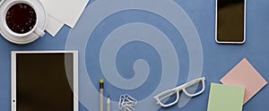 Overhead shot of office desktop. Telephone, tea cup, glasses, pencils, notebook, pen, potted plant on light background.Top view