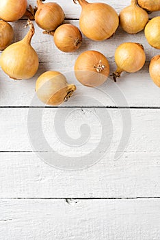 Overhead shot of onions on white wooden background with copyspace