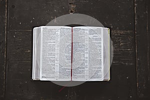 Overhead shot of an open bible on a black wooden surface