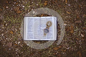 Overhead shot of an open book with an open compass on it on the ground