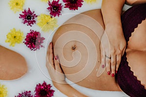 Overhead shot of a pregnant woman in a relaxing milk bath with flowers