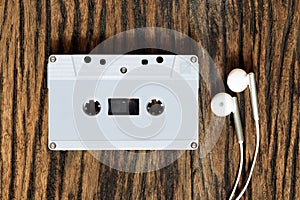 Overhead shot of retro old audio cassette tape with earphone on grunge vintage wood background, top view