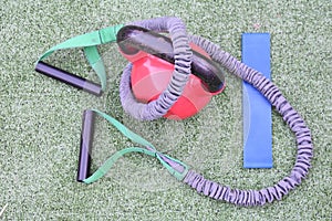 Overhead shot of round heavy weight, stretchy gym equipment and blue resistance band on grass photo