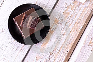 Overhead shot of a slice of chocolate cake on black ceramic plate on a wooden table