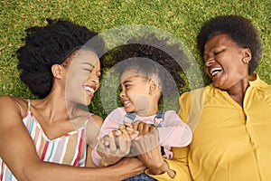 Overhead Shot Of Smiling Multi-Generation Female Family Lying On Grass In Garden Together