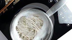Overhead Shot of Soba Noodles Boiling in a Metal Pot on an Induction Stove
