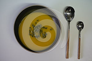 Overhead shot of tasty delicious pumpkin soup decorated with seeds and two spoons